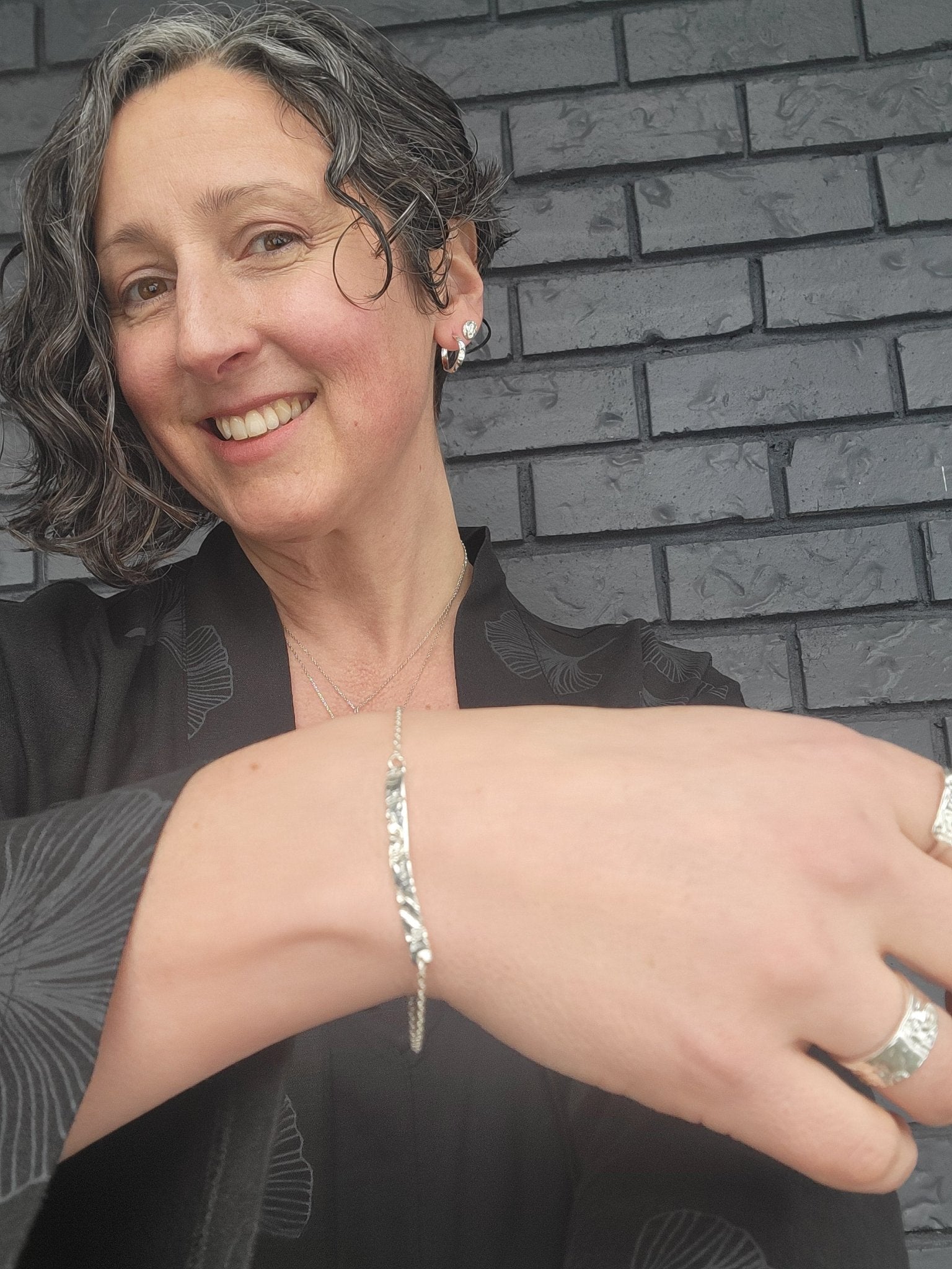 Model wearing sterling silver adjustable natural textured bracelet and rings