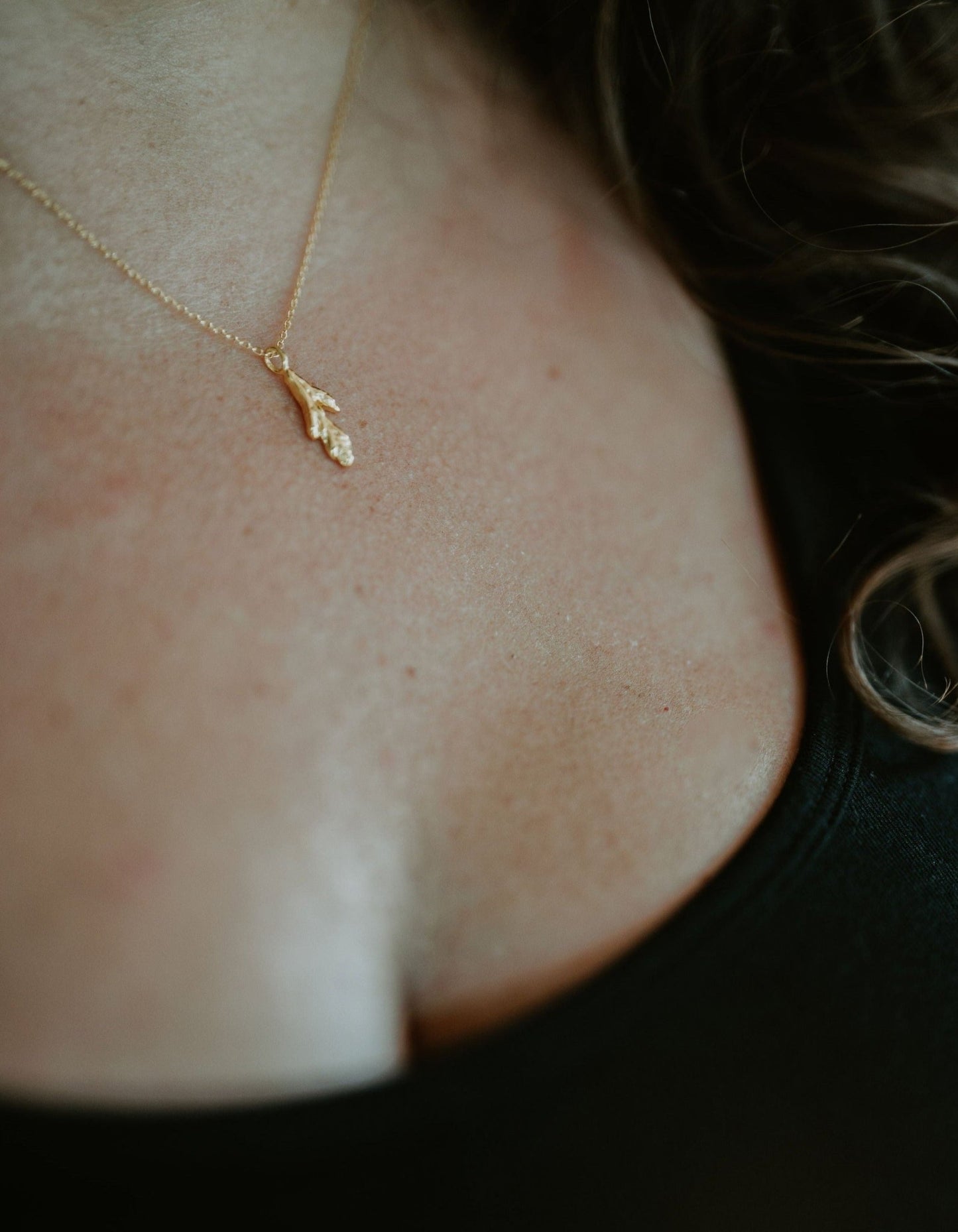 model wearing yellow gold plated little cedar leaf pendant necklace closeup