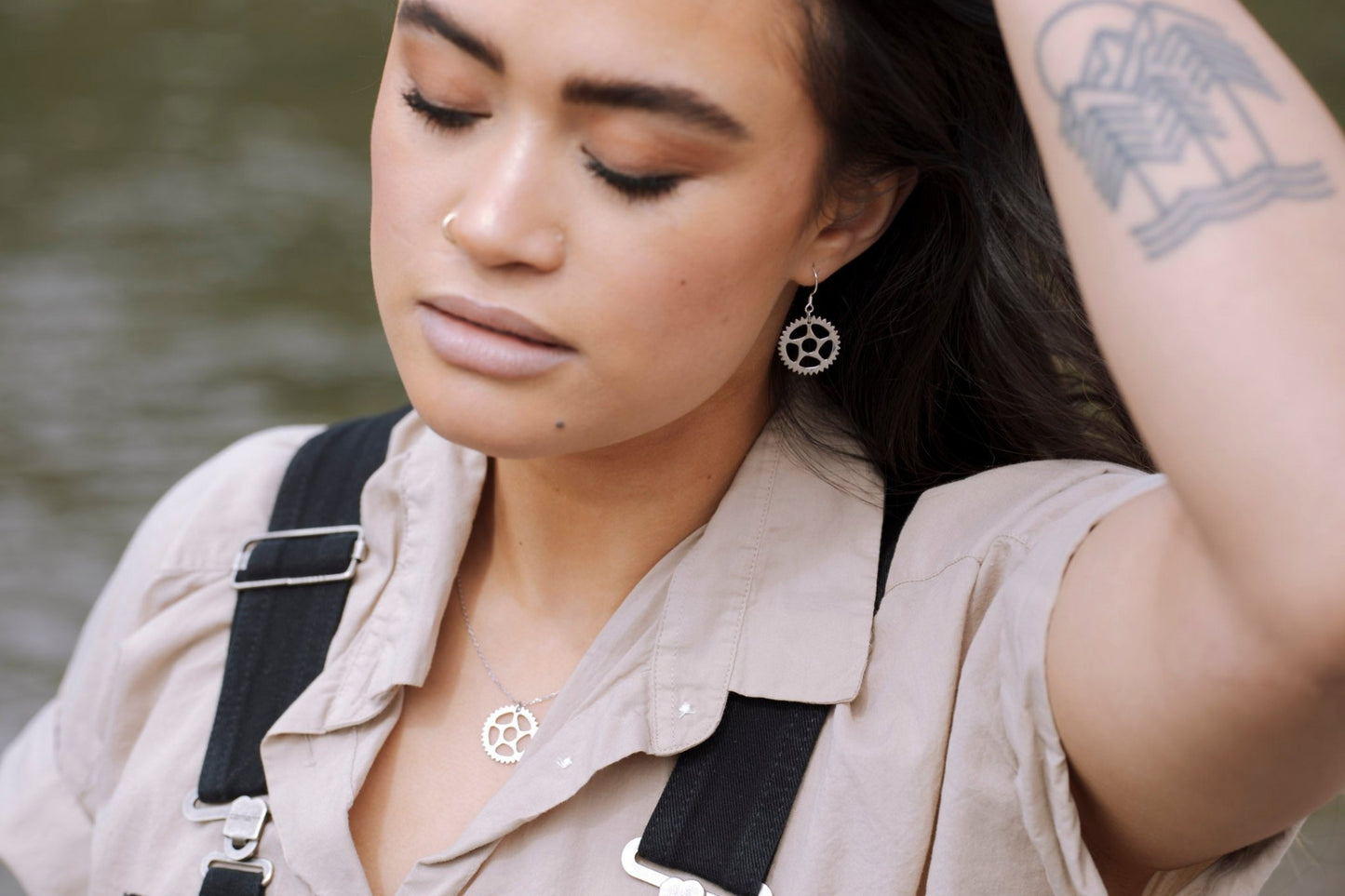 model wearing 925 Sterling silver bike chain ring design drop earrings and matching necklace with a blur water background-1