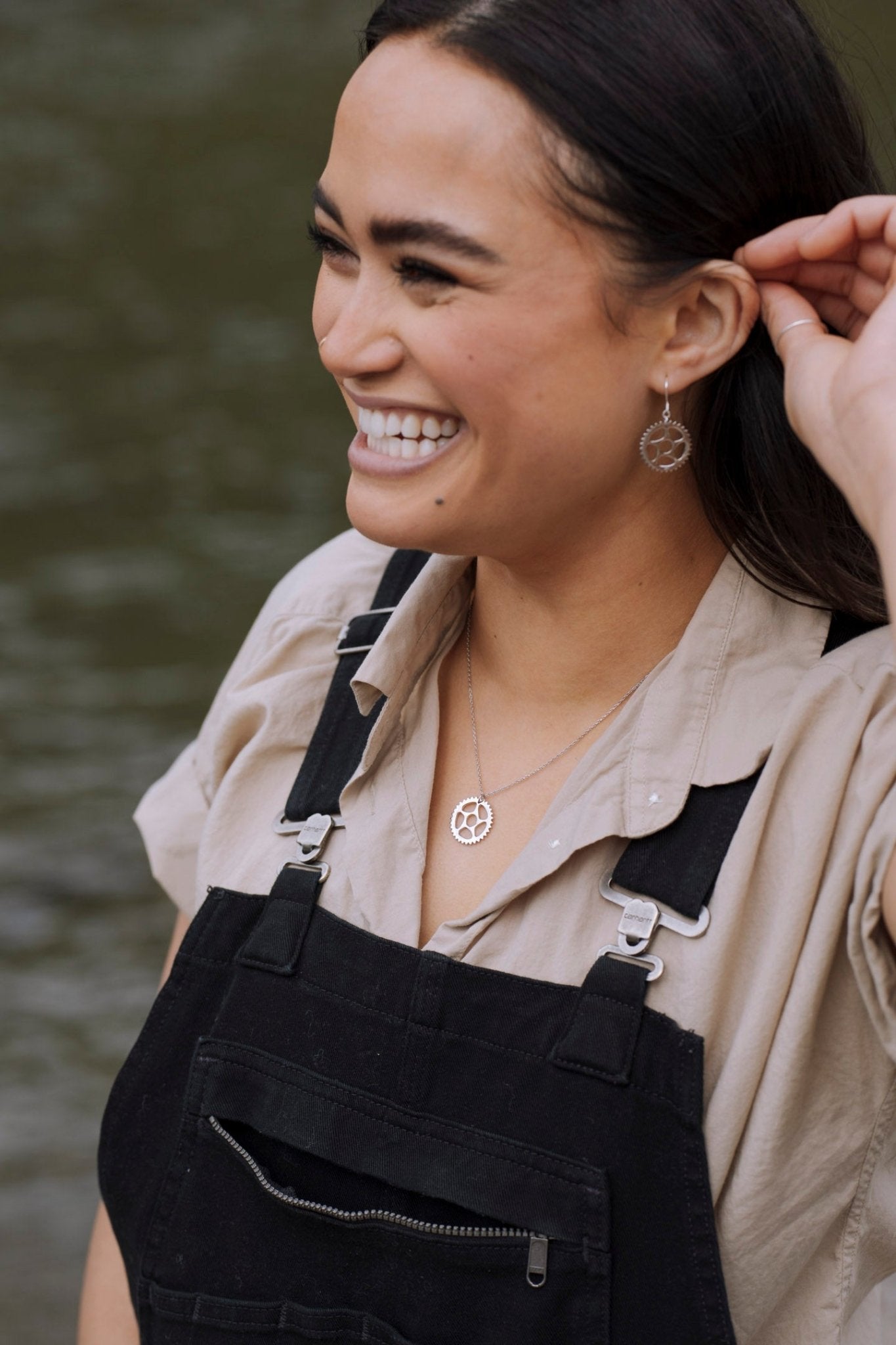 smiling woman wearing a 925 sterling silver bike chain ring necklace and chain ring earrings with nature background