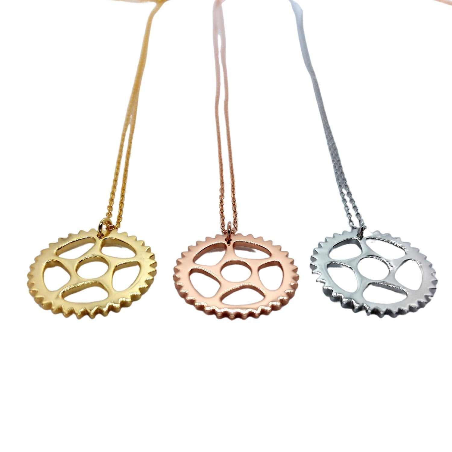 3 bike chain ring, cog or sprocket pendant necklace in gold, rose gold, and silver on a white background