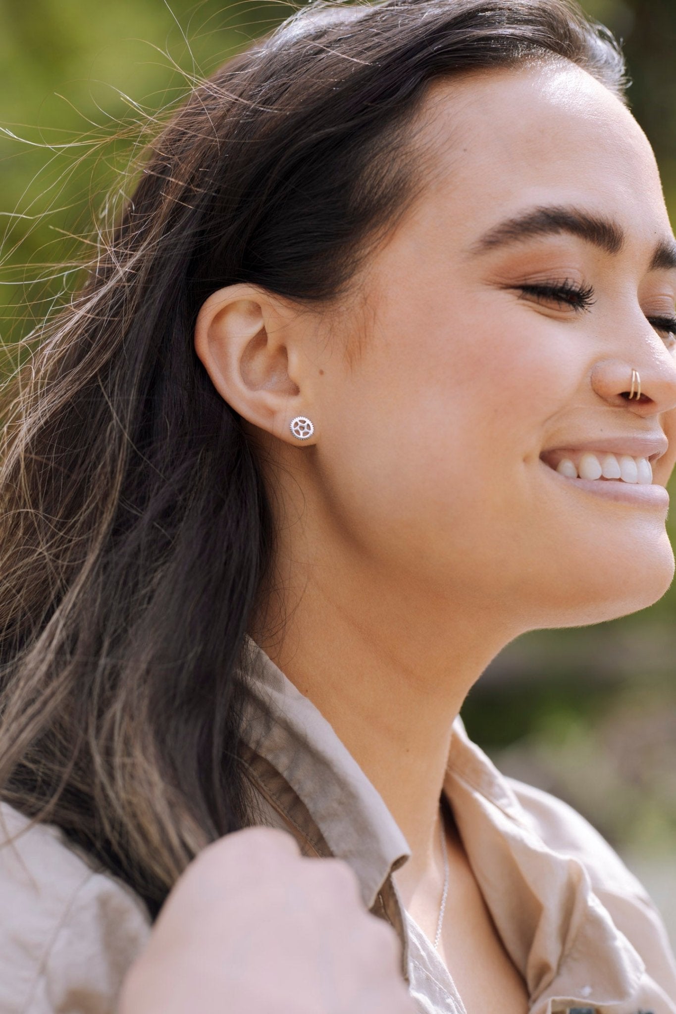 smiling woman wearing sterling silver bike chain ring stud earrings with nature background