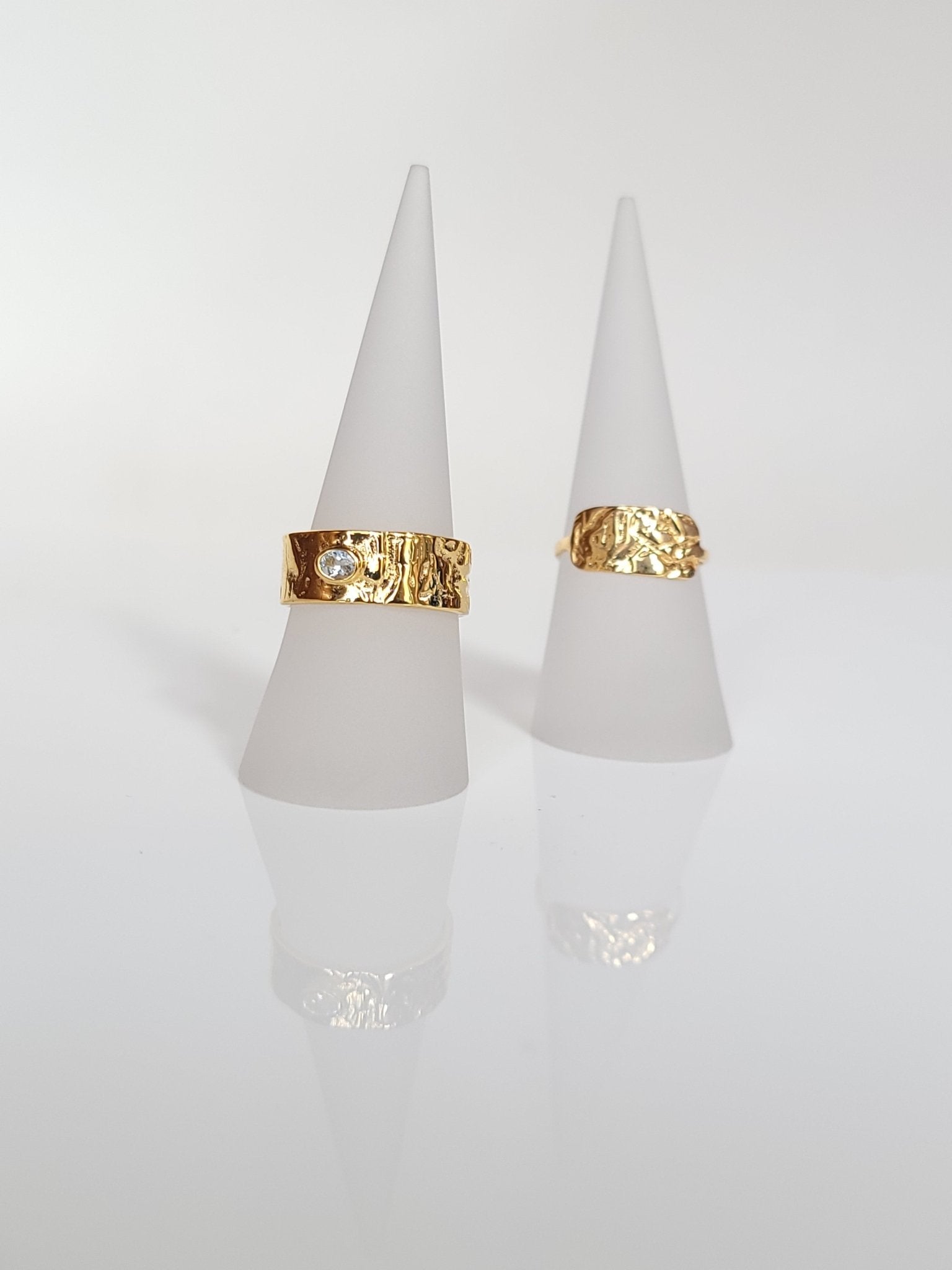 two gold vermeil rings with natural textures of wood displayed on frosted ring holder