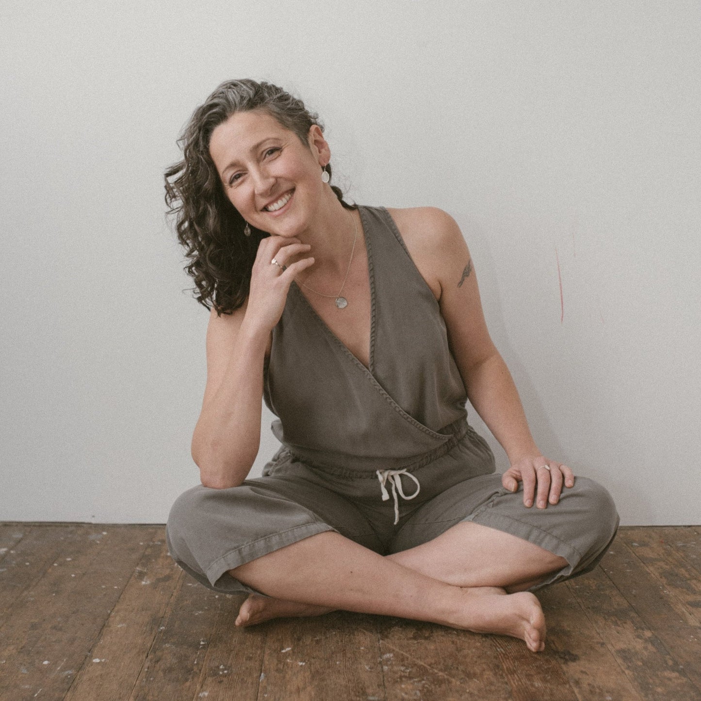 model wearing rose sterling silver vita pendant necklace sitting on wood floor