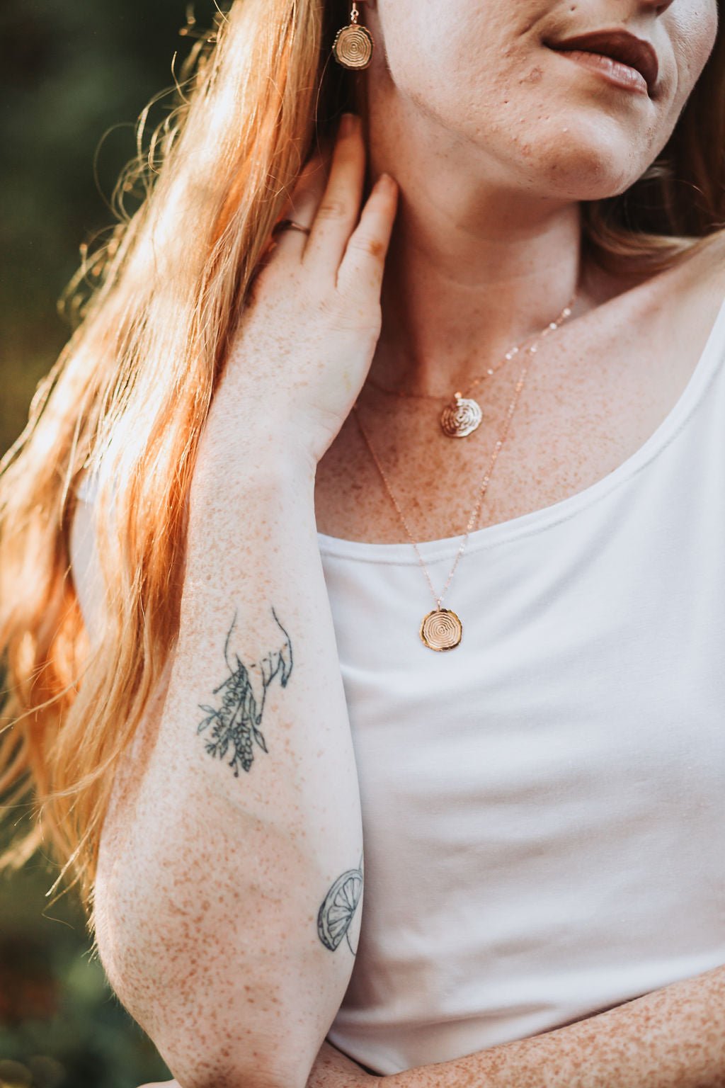 model wearing yellow gold plated vita pendant necklace with nature background