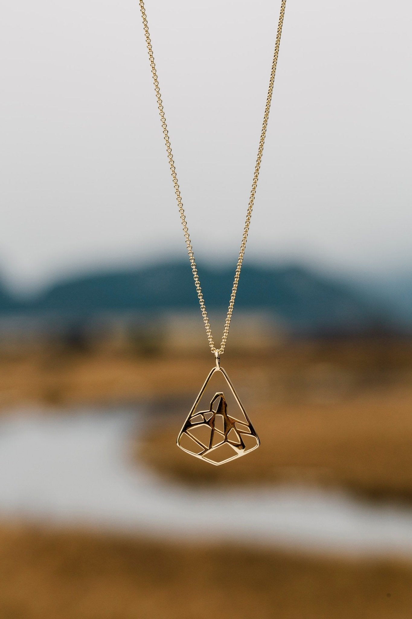 Gold Black Tusk pendant necklace  shown against blurred river background