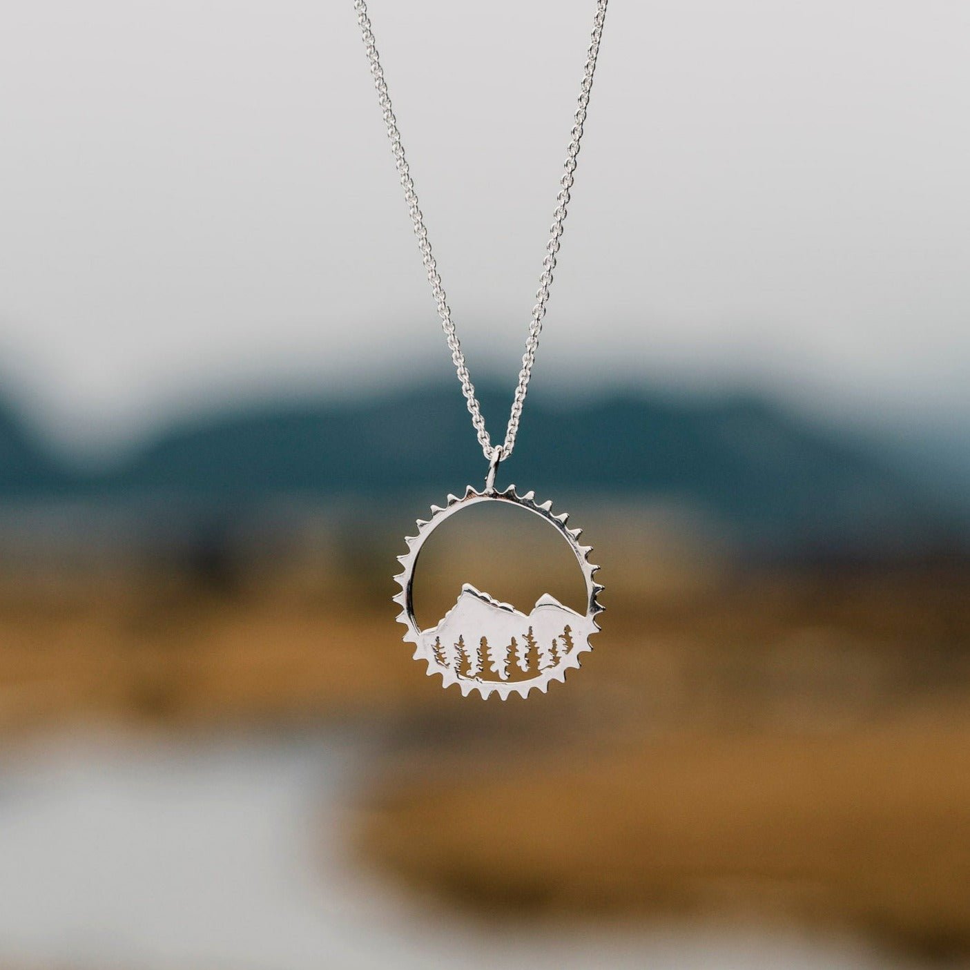 amore pendant necklace shown with blurred blurred river background