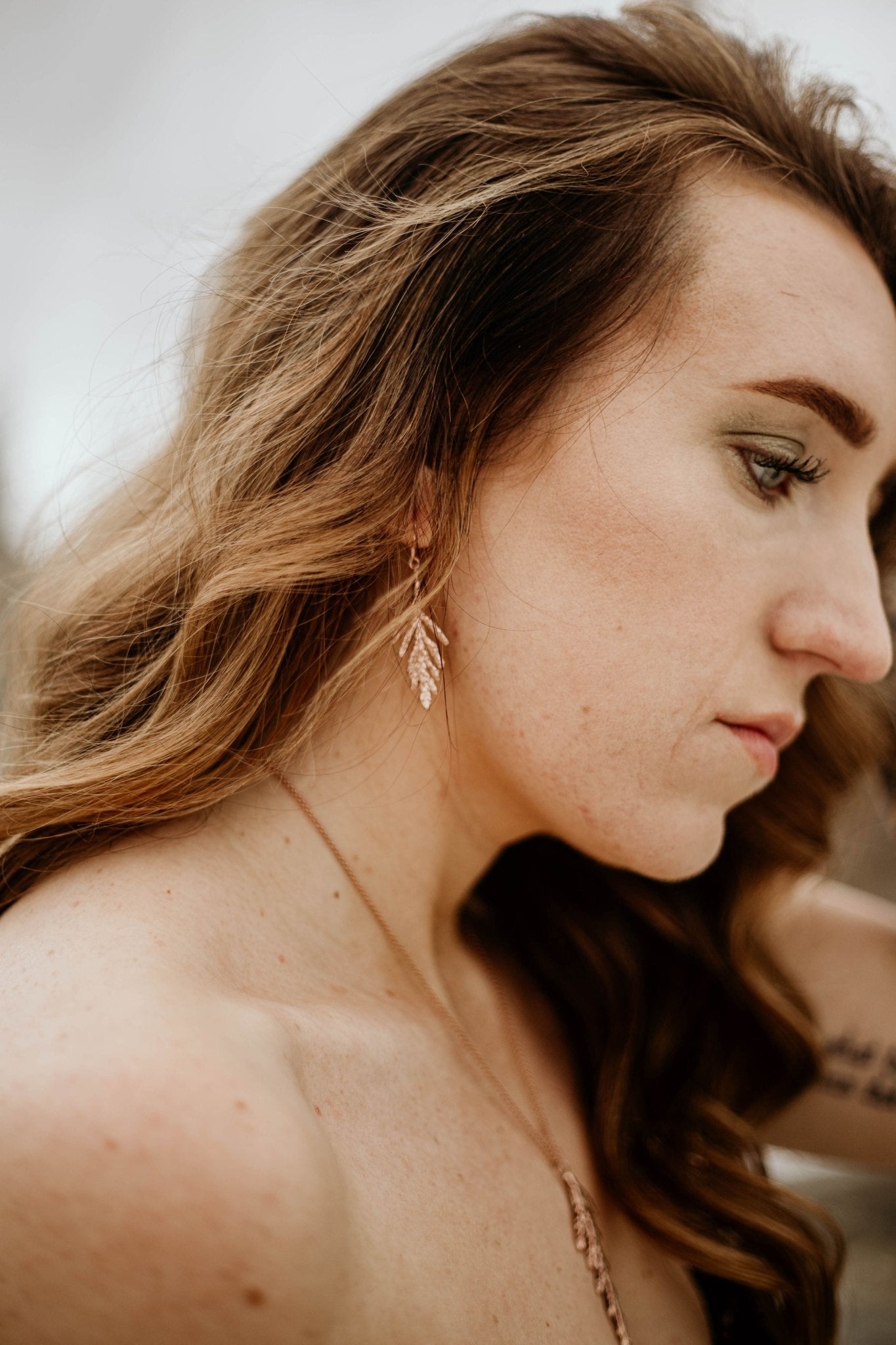 model wearing 18k gold plated cedar leaf design dangle earrings