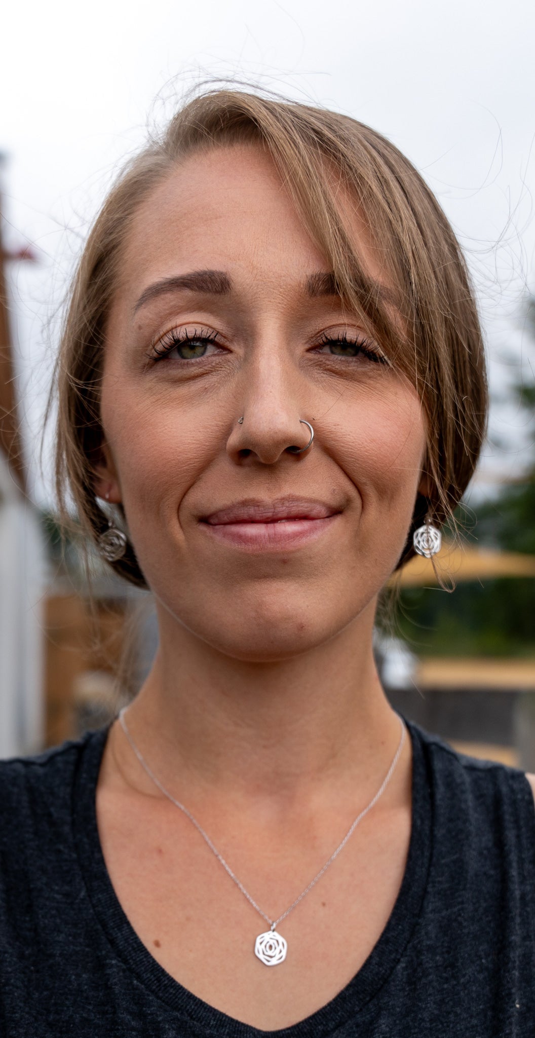 model close up wearing matching rose dangle earrings and rose flower necklace in silver