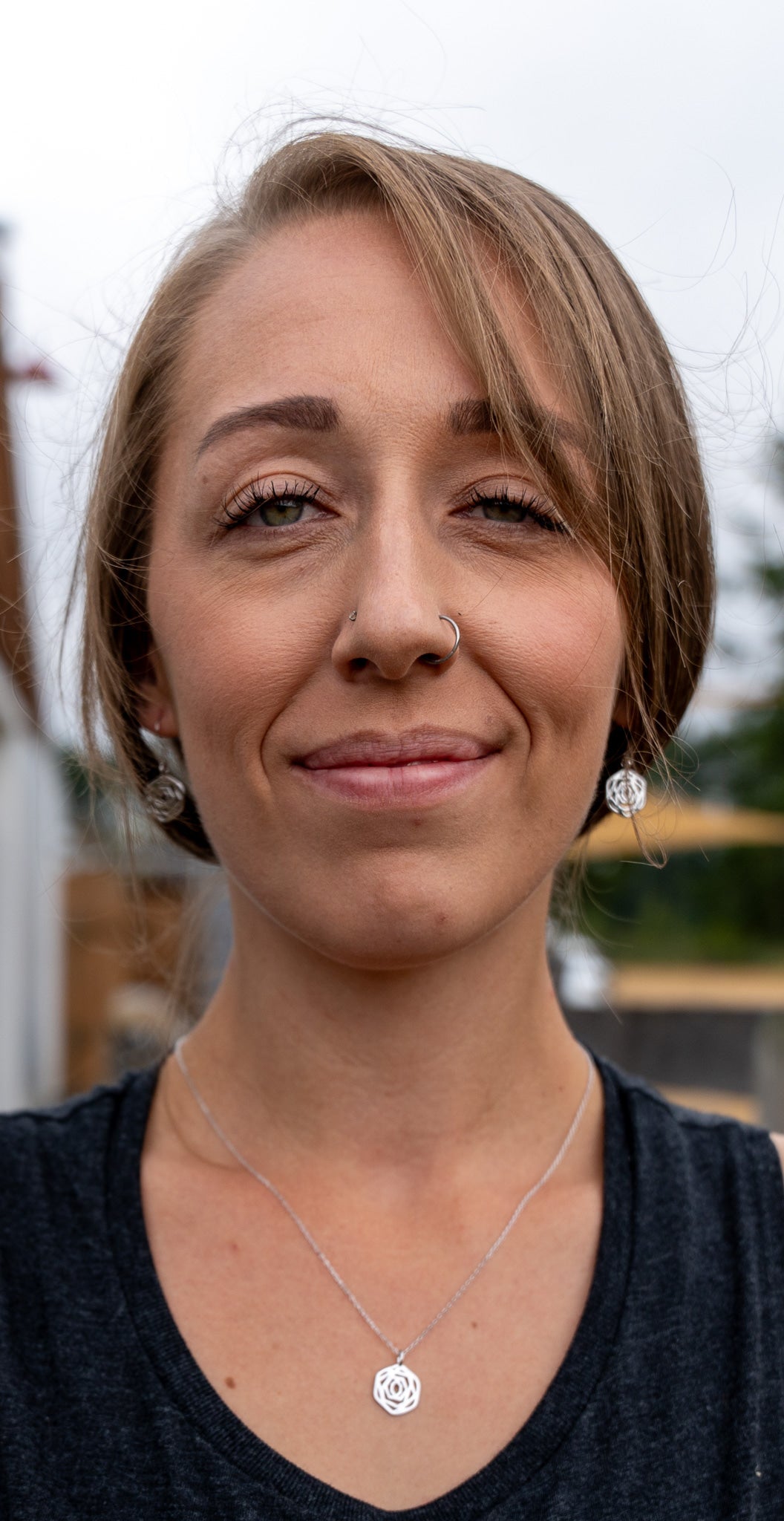 model close up wearing matching rose dangle earrings and rose flower necklace in silver