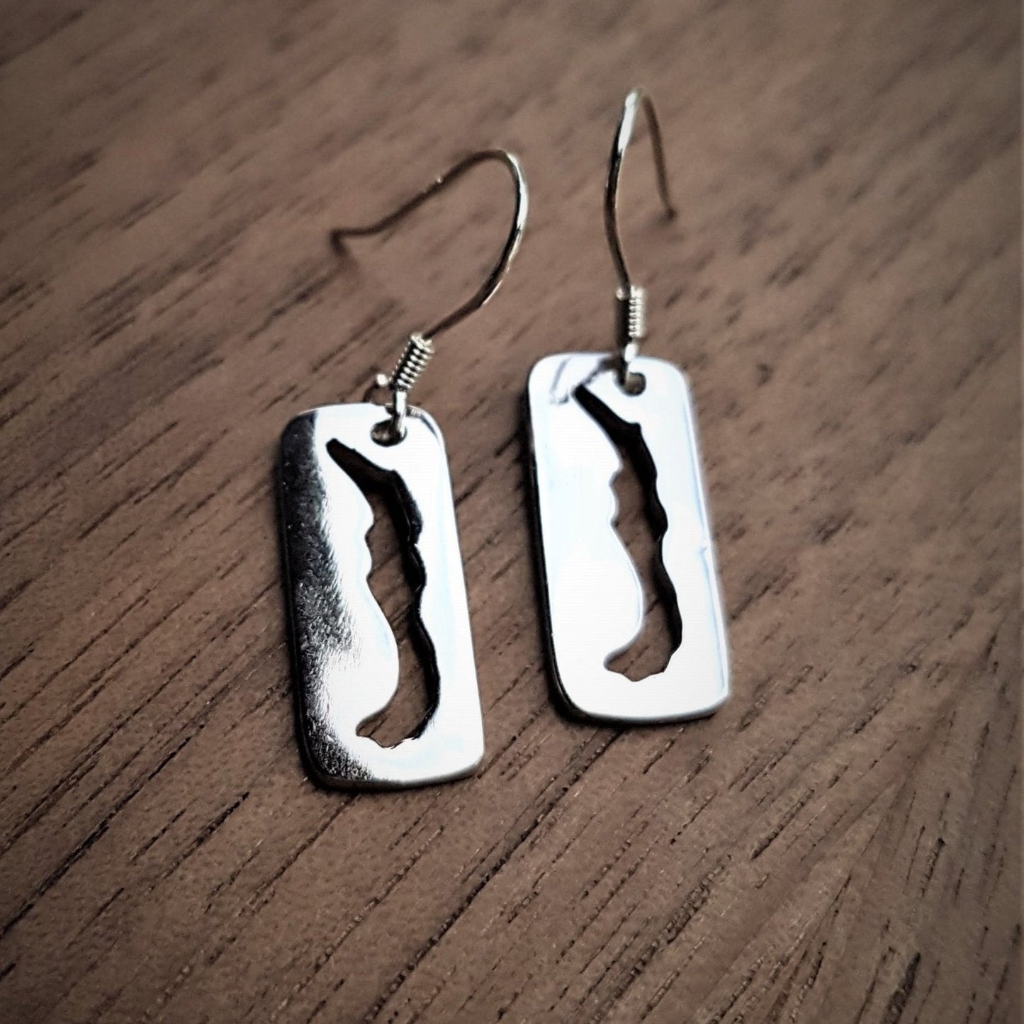 sterling silver rectangular dangle earring with a cut-out of Savary Island on French ear wires with wood background