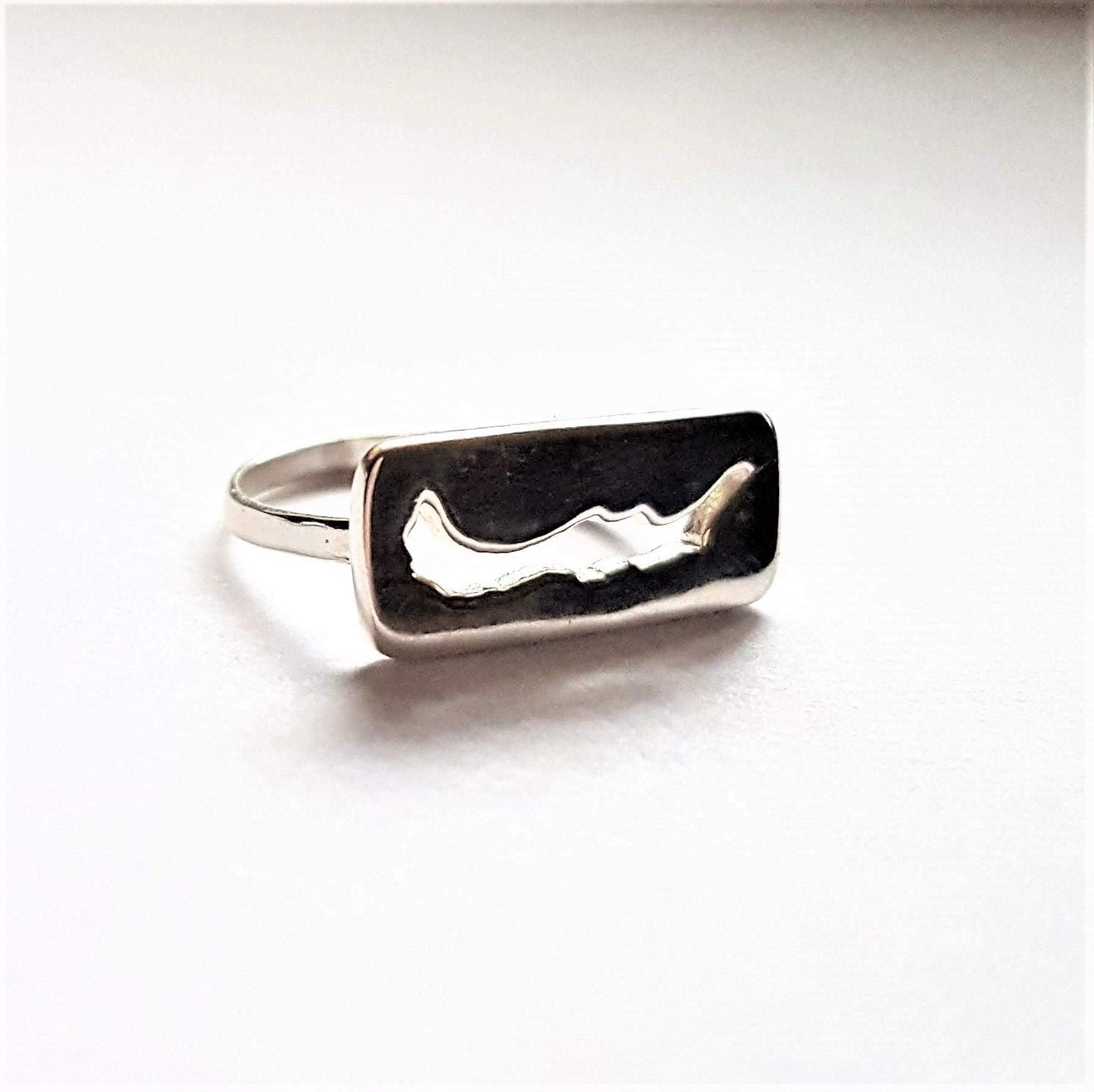 Savary island Ring. sterling silver ring with rectangle insignia with savary island shape cut out on white background