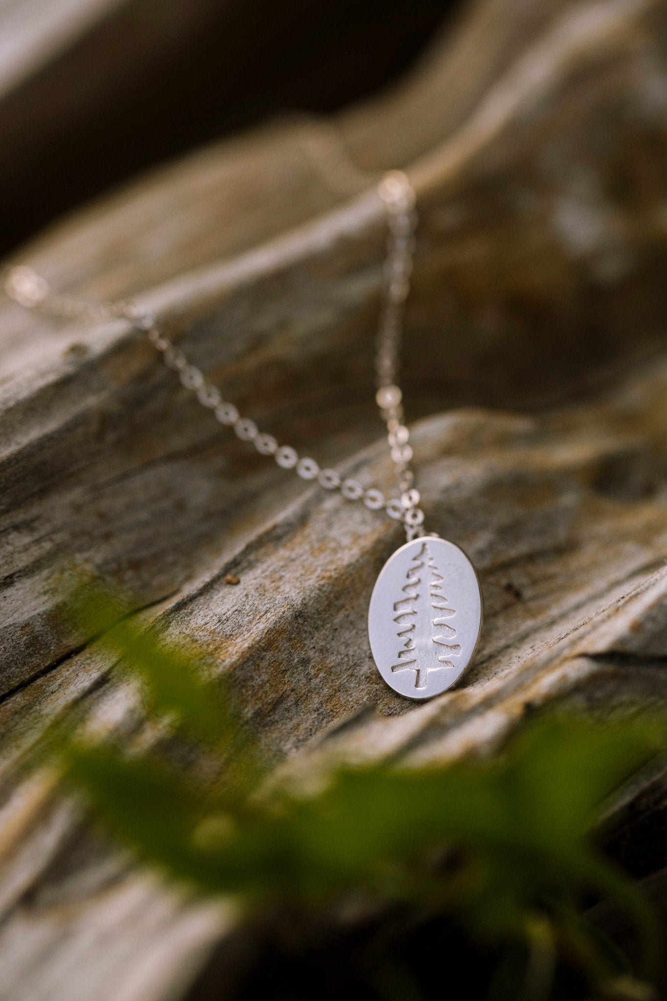 925 sterling silver Sitka Tree embossed into Oval Pendant Necklace on wood background