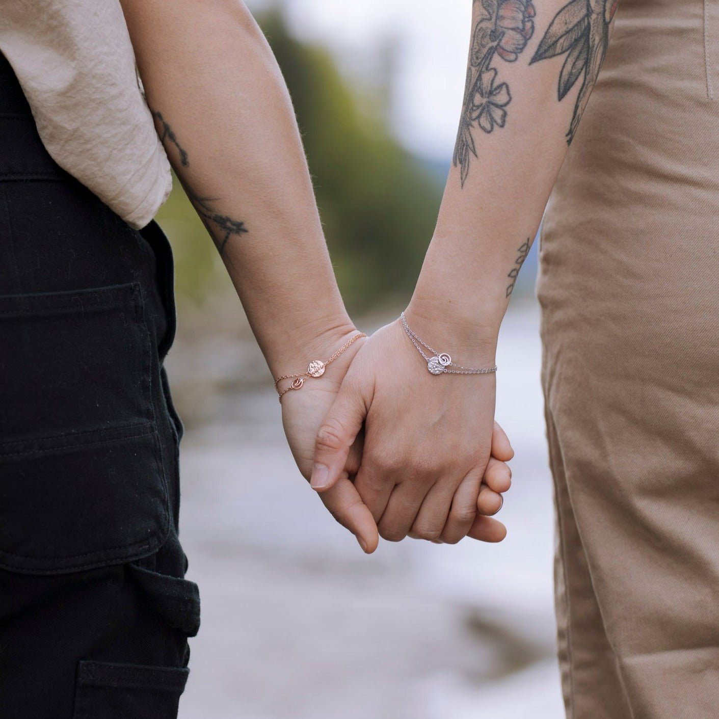 Two models holding hands and wearing Sol adjustable bracelets with textured circle charms