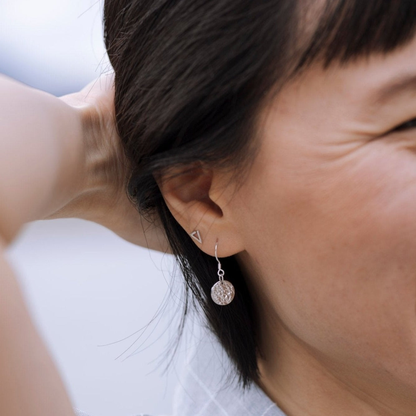 model wearing sterling silver Sol textured circle drop earrings closeup