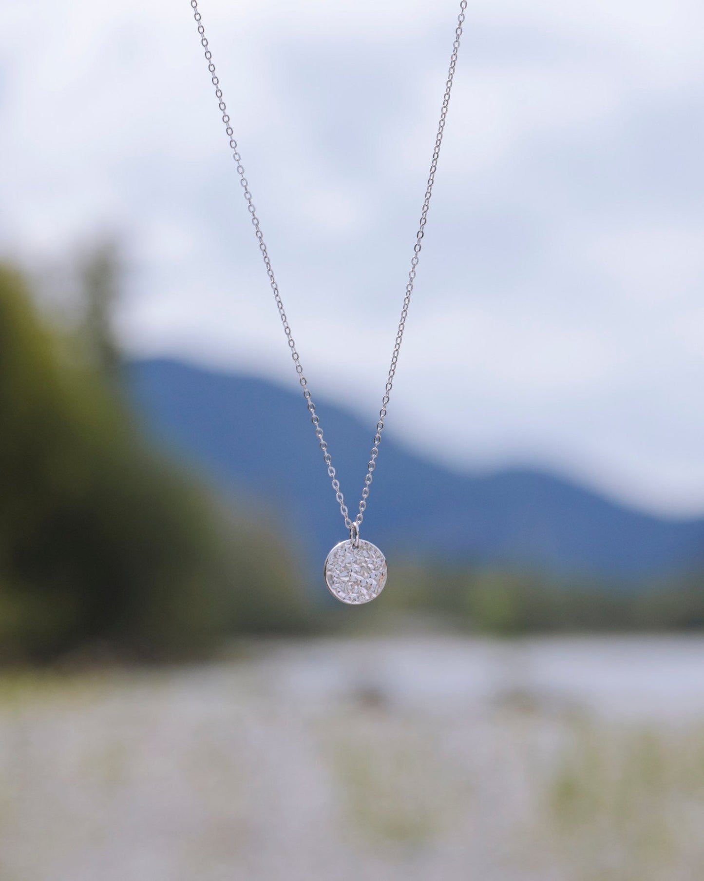 Sterling Silver Sol Textured Small Circle Pendant Necklace on nature blur background - 1
