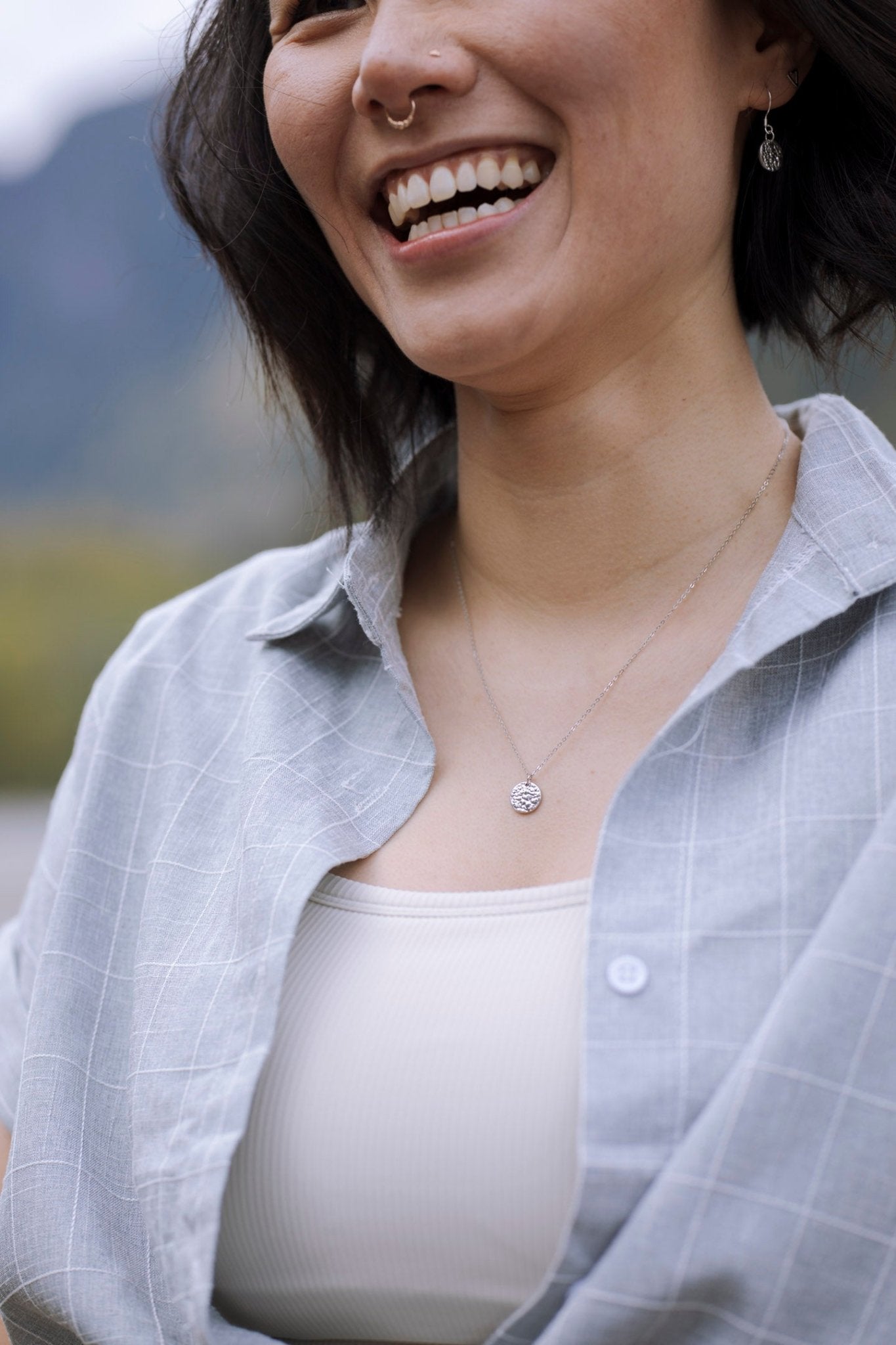 model wearing sterling silver Sol Textured Small Circle Pendant Necklace with nature blur background