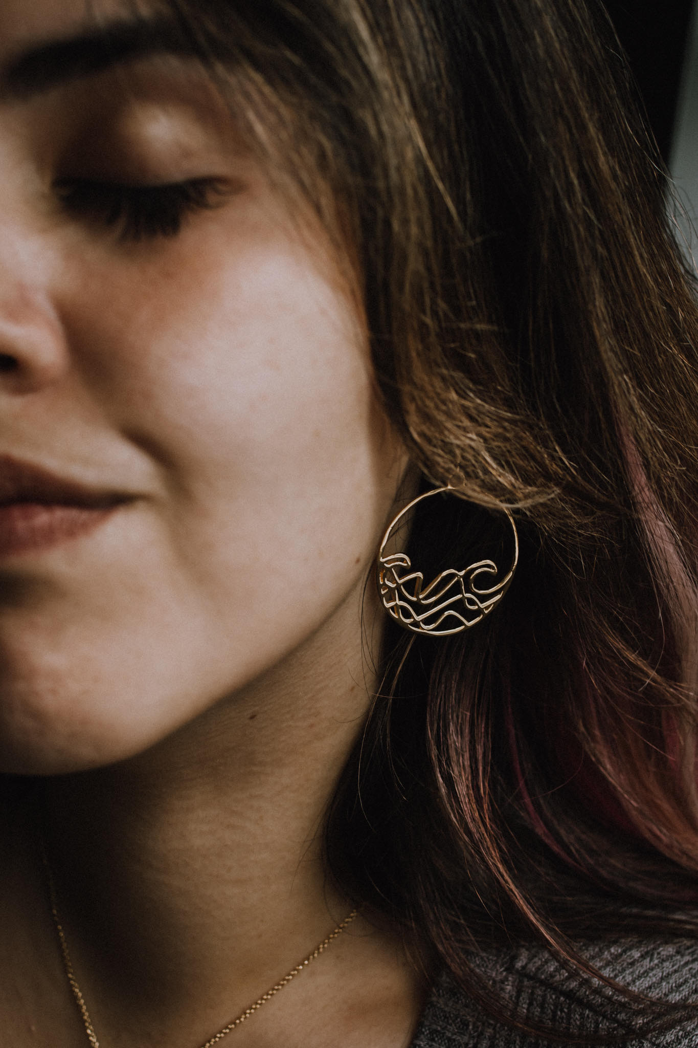 model wearing gold plated Sombrio Circle Surf Wave Earrings closeup