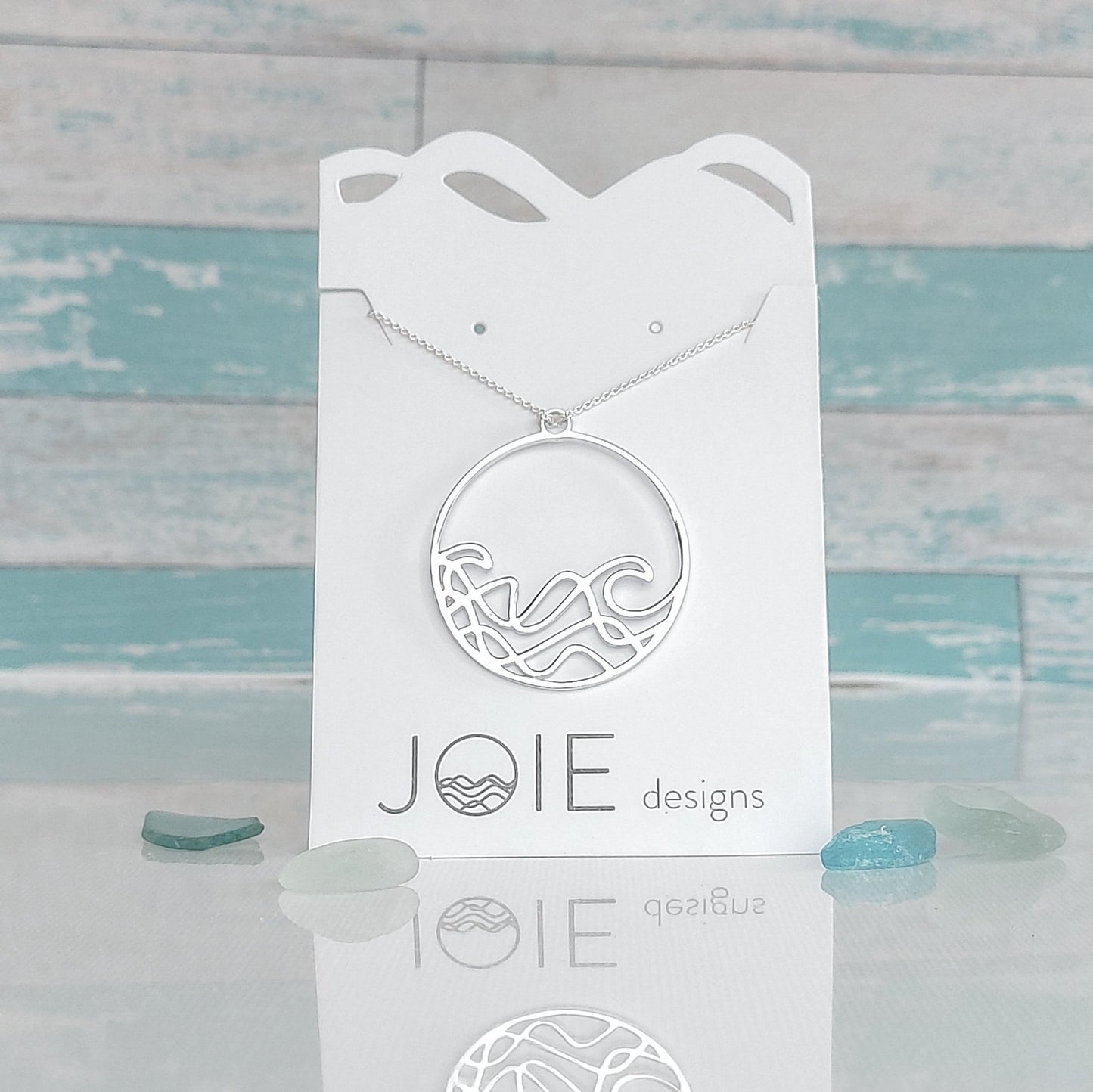 sterling silver round beach wave necklace. surf wave pendant on chain necklace on white jewelry card