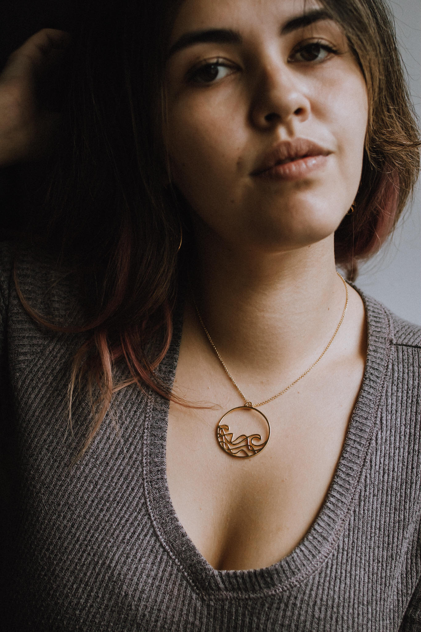 model wearing gold  Sombrio beach  round wave necklace. surf wave pendant on chain necklace.
