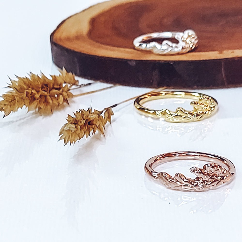 silver and 18k plated rose and gold cedar leaf thuja rings shown on wood cross section