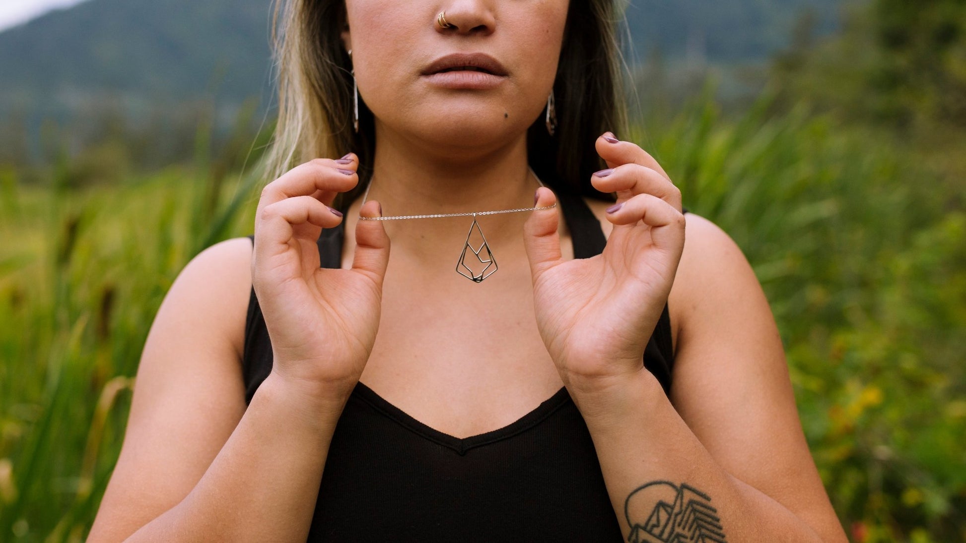 Model wearing sterling silver wolf pendant necklace holding chain