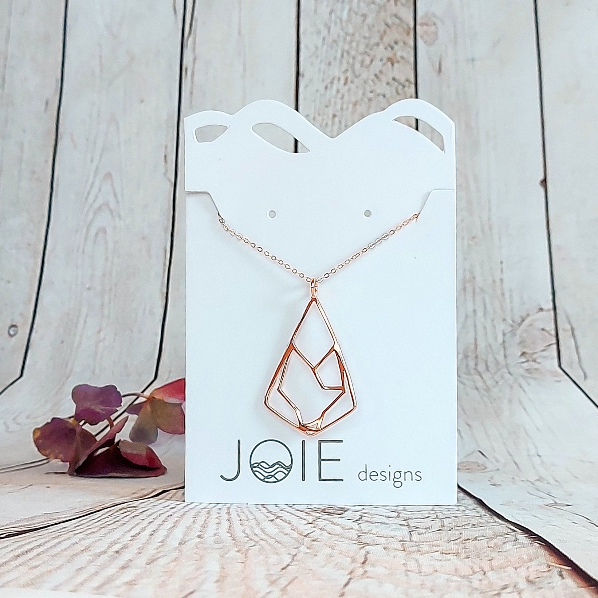 18k plated rose gold wolf pendant necklace displayed on a white jewellery card with flowers